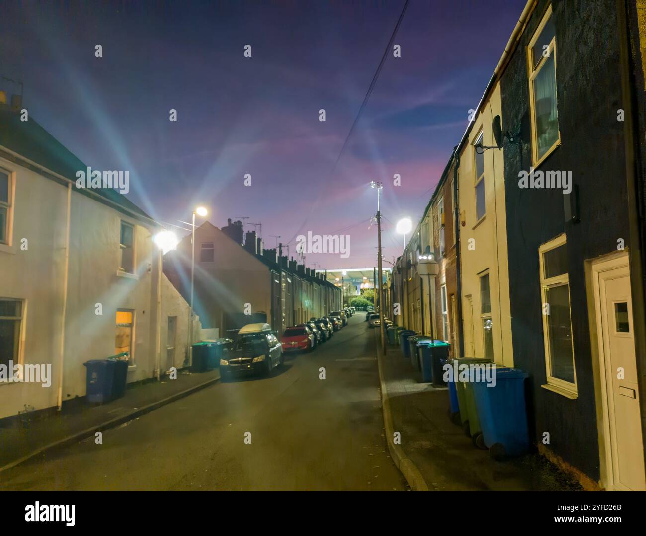 I riflettori dello stadio Field Mill tra una fila di case a schiera a Mansfield, Nottinghamshire, Regno Unito Foto Stock