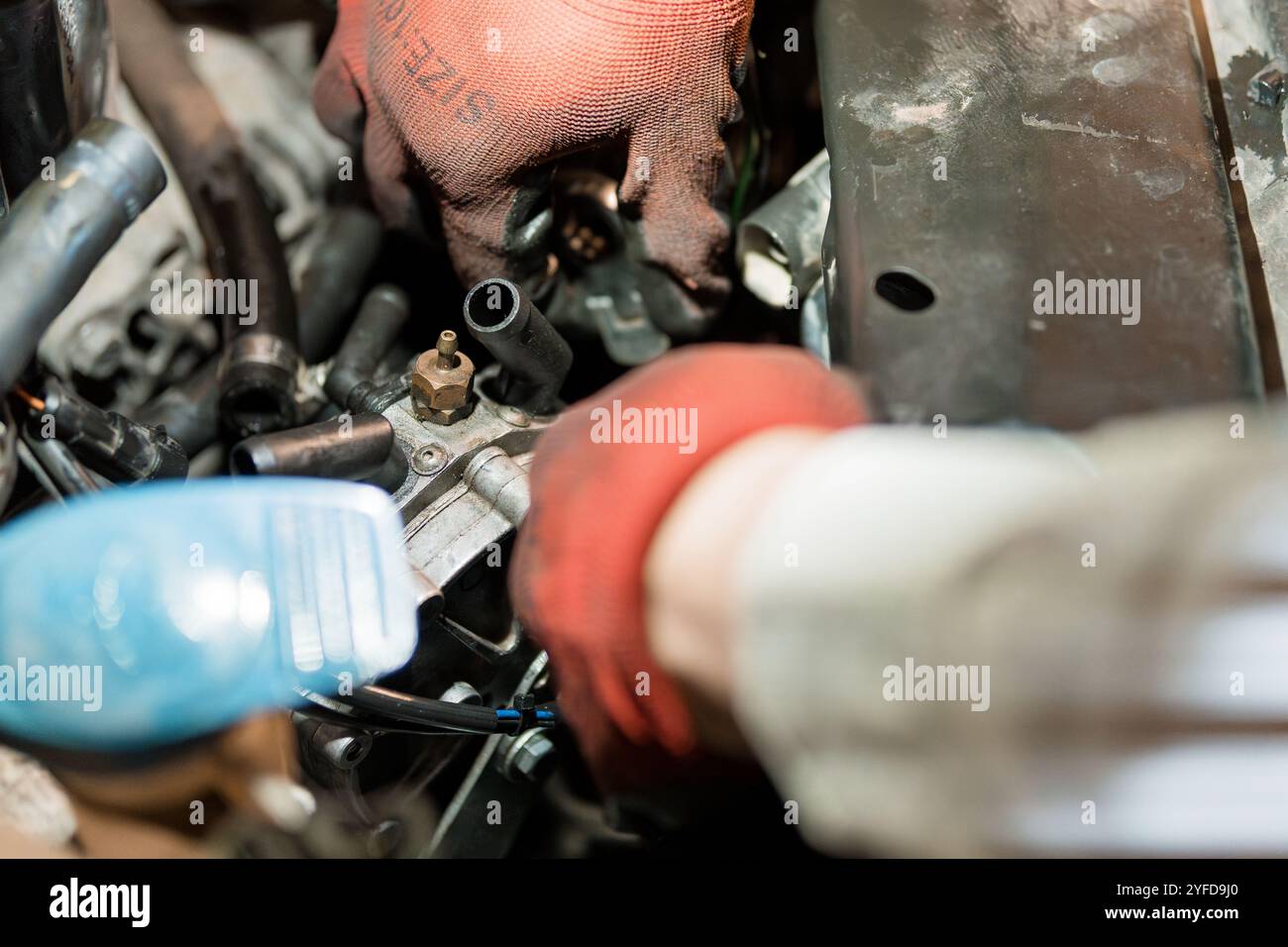 Primo piano delle mani di un meccanico che lavora su un componente del motore. Foto Stock