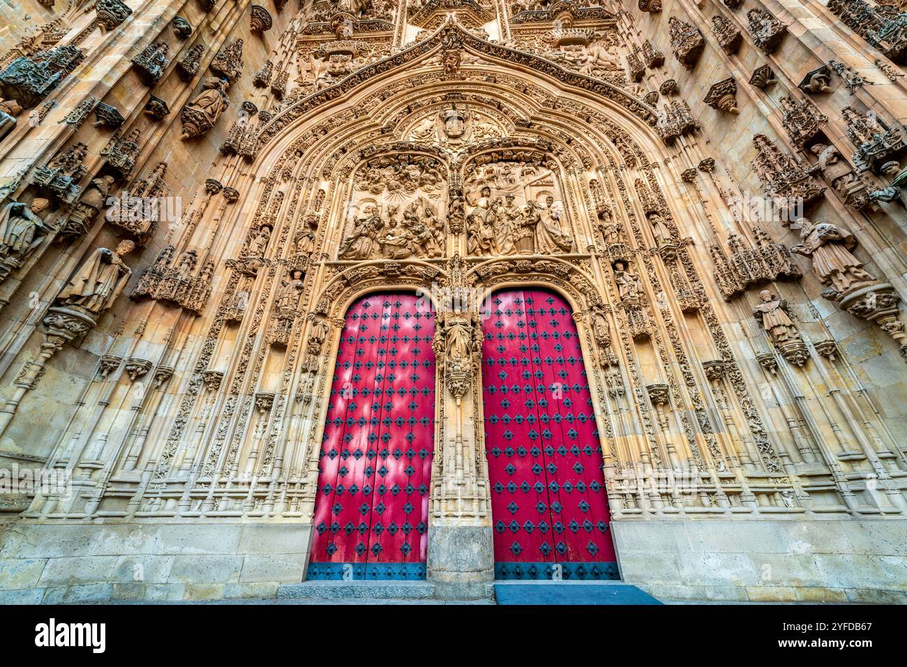 Vista esterna della Cattedrale di Salamanca con porte rosse e statue religiose in pietra scolpita, ingresso decorativo ad arco a Salamanca, Spagna. Foto Stock