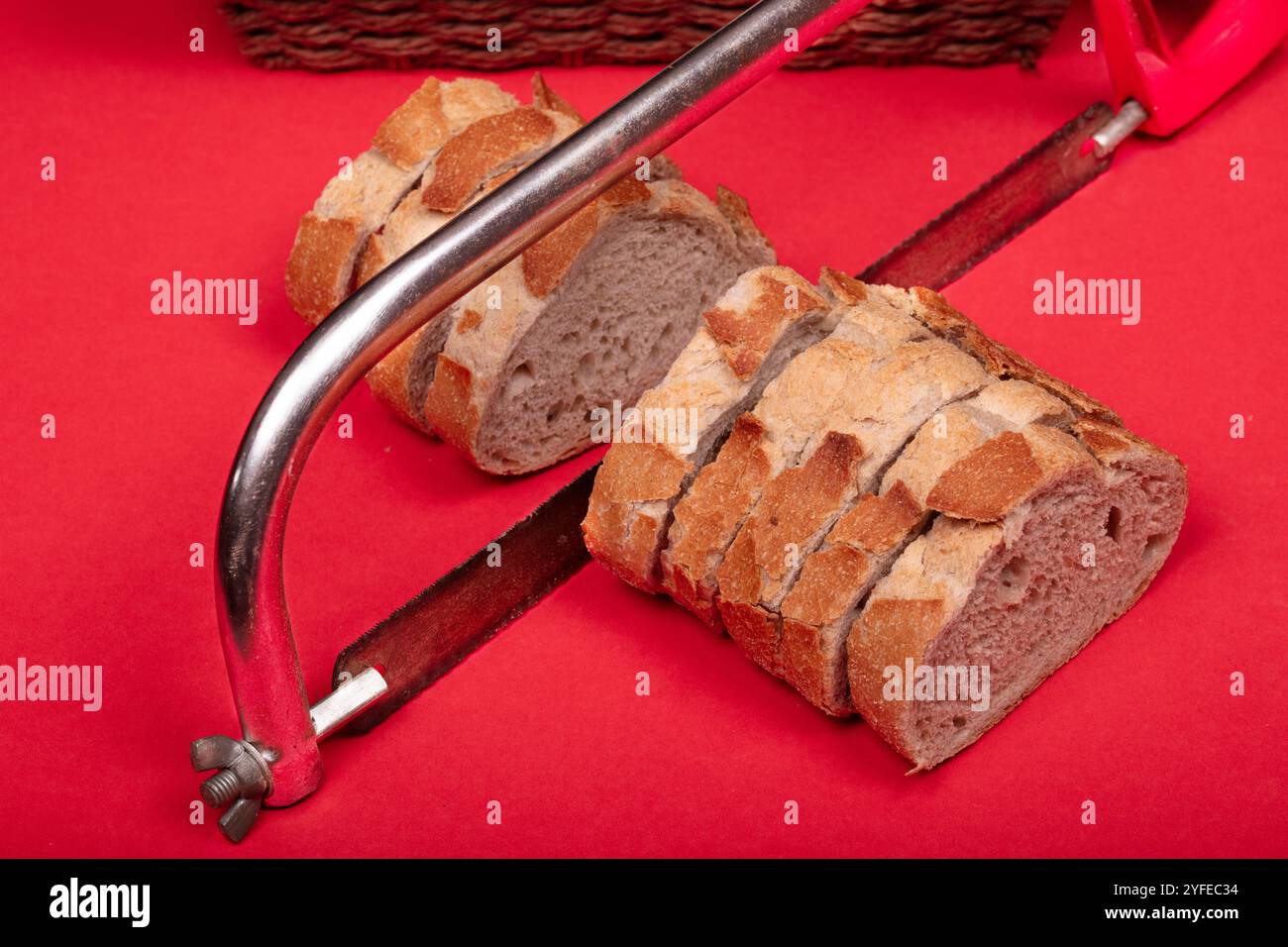 Concetto creativo di pane a fette con seghetto su sfondo rosso - immagine unica per immagini artistiche, astratte e relative al cibo Foto Stock