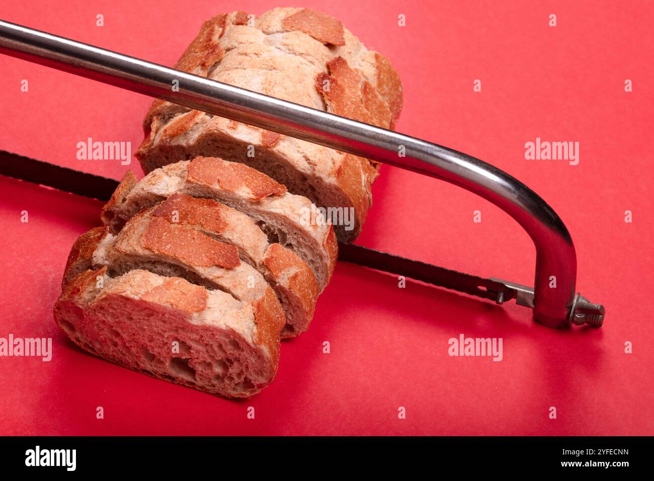 Concetto creativo di pane a fette con seghetto su sfondo rosso - immagine unica per immagini artistiche, astratte e relative al cibo Foto Stock