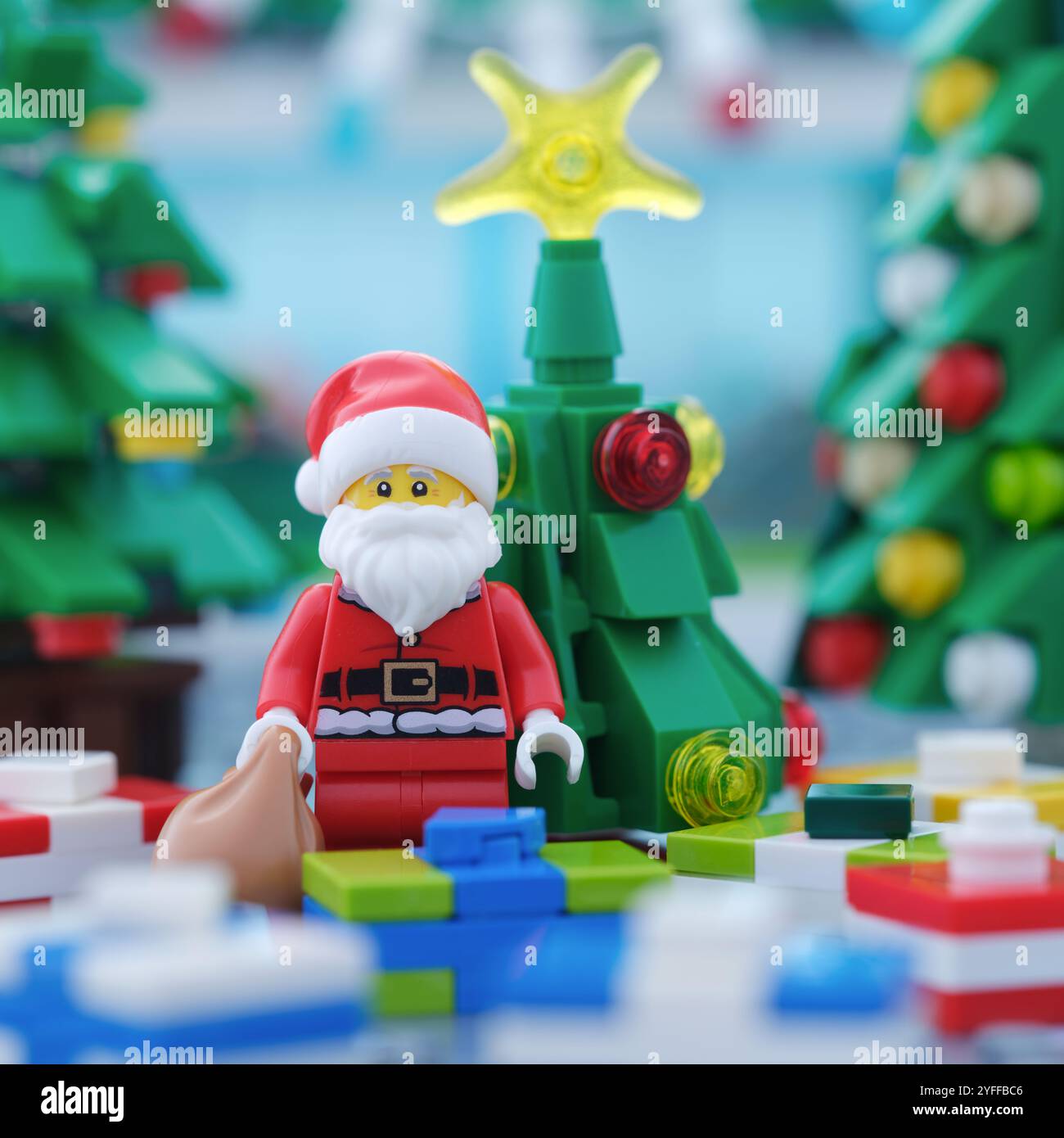 Tambov, Federazione Russa - 4 novembre 2024 Una minifigura Lego Babbo Natale con un sacco di regali in piedi davanti a un albero di Natale e un surrogato Foto Stock