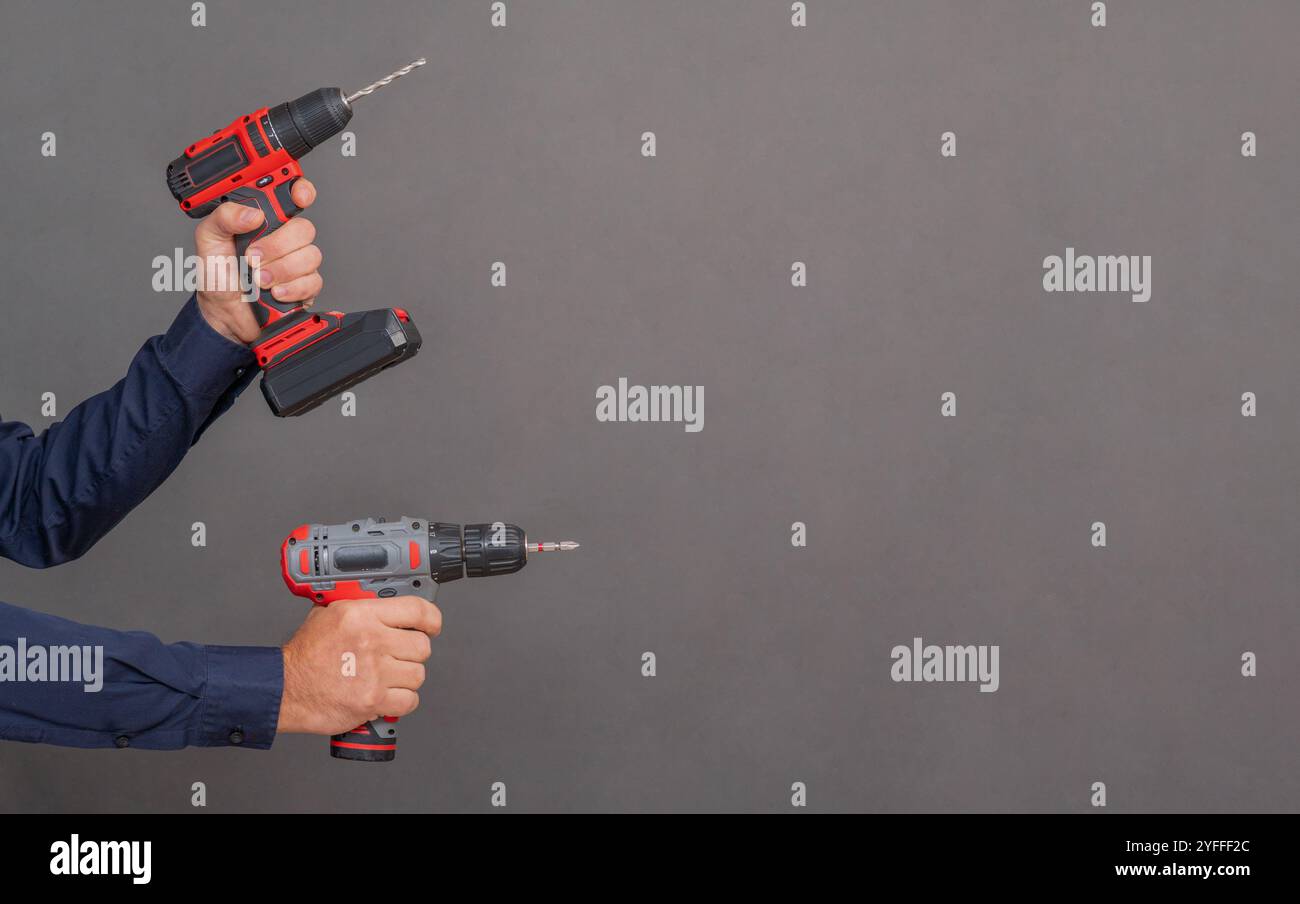 Cacciaviti a batteria con mani su sfondo grigio. copia spazio Foto Stock