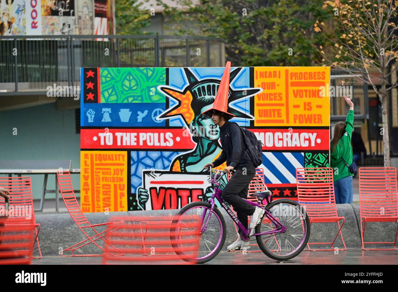 Philadelphia, Stati Uniti. 4 novembre 2024. Un ciclista con un cono stradale come headwear bike ha superato un progetto Mural Arts a Love Park, Philadelphia, PA, USA il 4 novembre 2024, giorno prima delle storiche elezioni presidenziali degli Stati Uniti. (Foto di Bastiaan Slabbers/Sipa USA) credito: SIPA USA/Alamy Live News Foto Stock