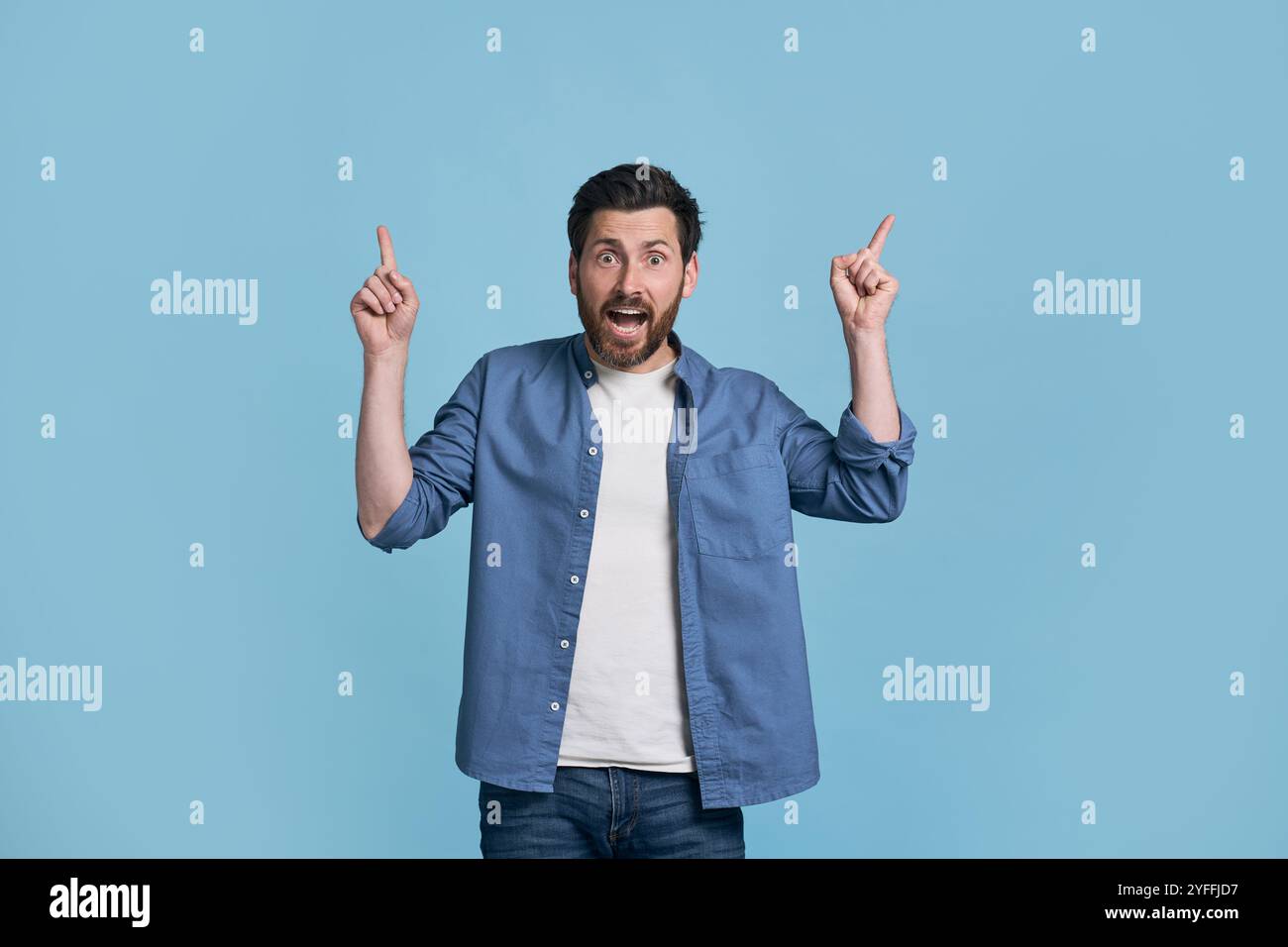 Uomo eccitato con la bocca aperta e gli occhi spalancati puntati con entrambe le mani, sorpreso da una promozione inaspettata o da una vendita incredibile Foto Stock
