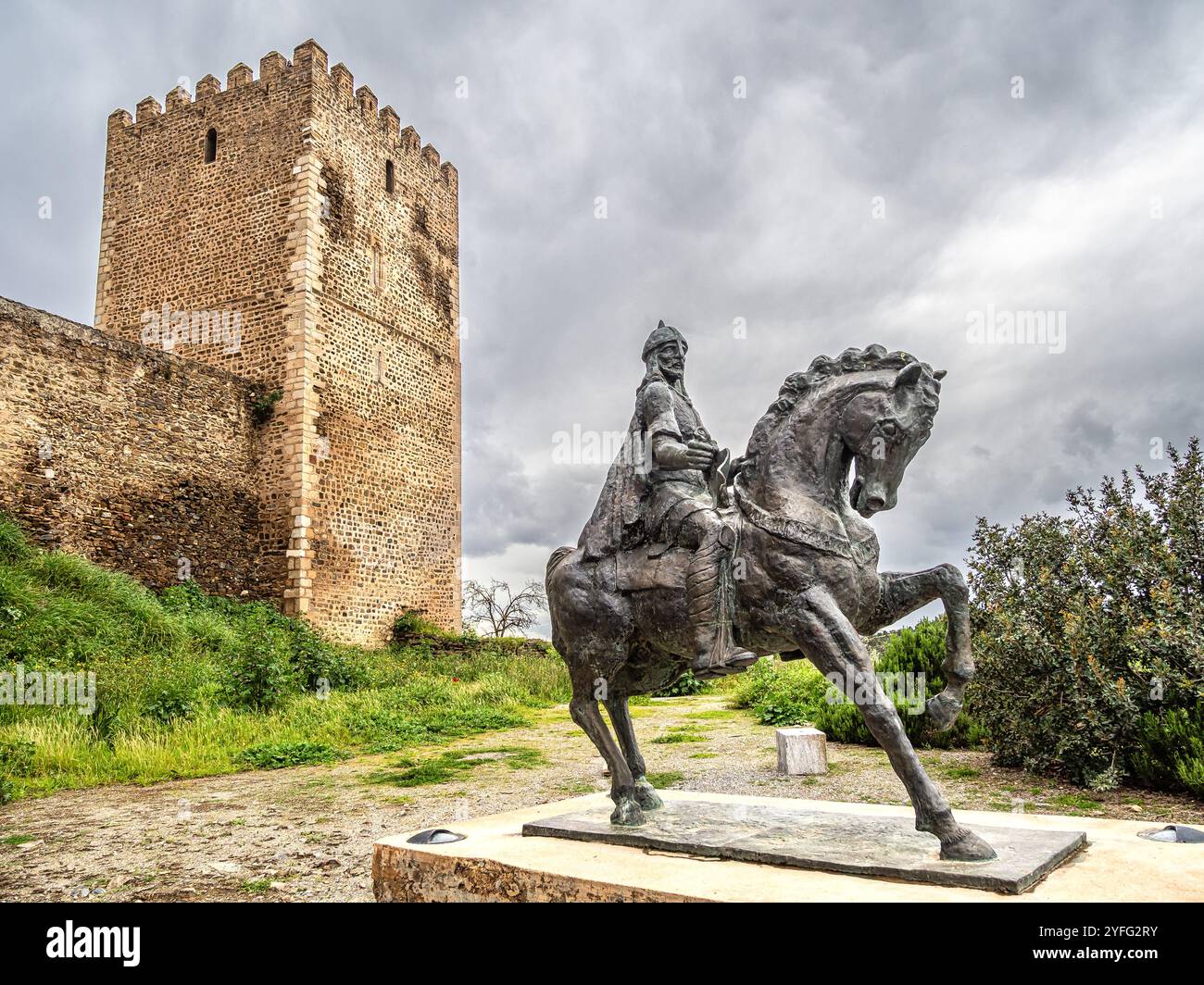 Una statua equestre di Ibn Qasi, proclamato leader politico e spirituale del regno taifa di Mertola, con la torre del castello di Mertola Foto Stock