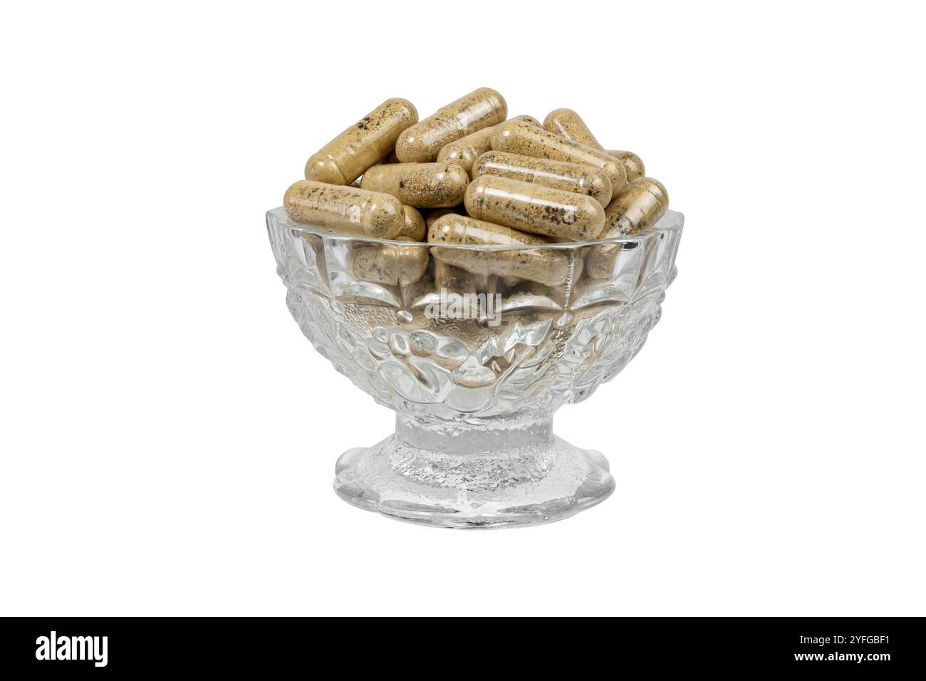 Una foto chiara e ravvicinata di capsule trasparenti riempite di polvere di erbe, esposte in una ciotola di vetro ornata contro una superficie piana, isolata su fondo bianco Foto Stock