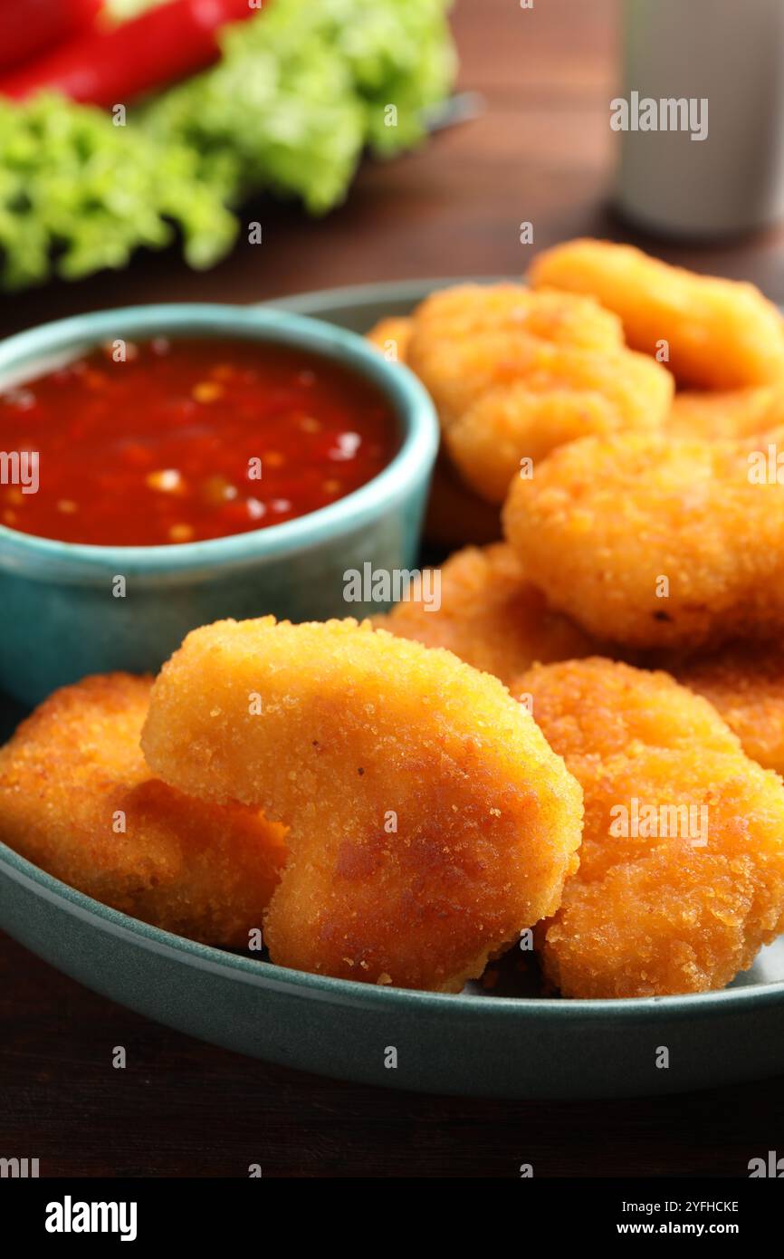 Piatto con salsa al peperoncino caldo e pepite sul tavolo, primo piano Foto Stock