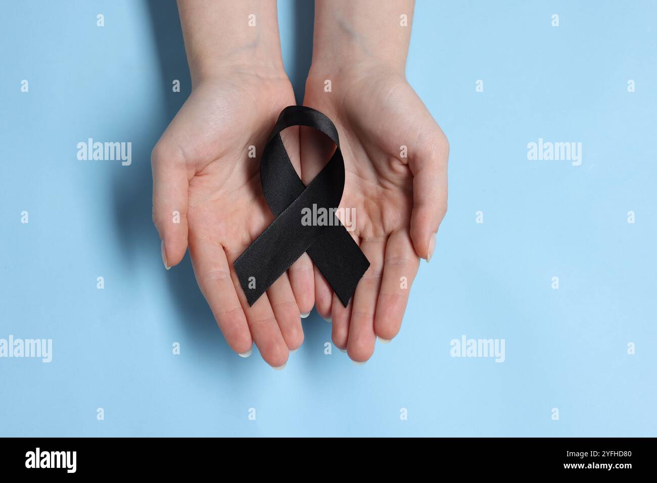 Donna con nastro nero su sfondo azzurro, vista dall'alto. Concetto di melanoma e lutto Foto Stock
