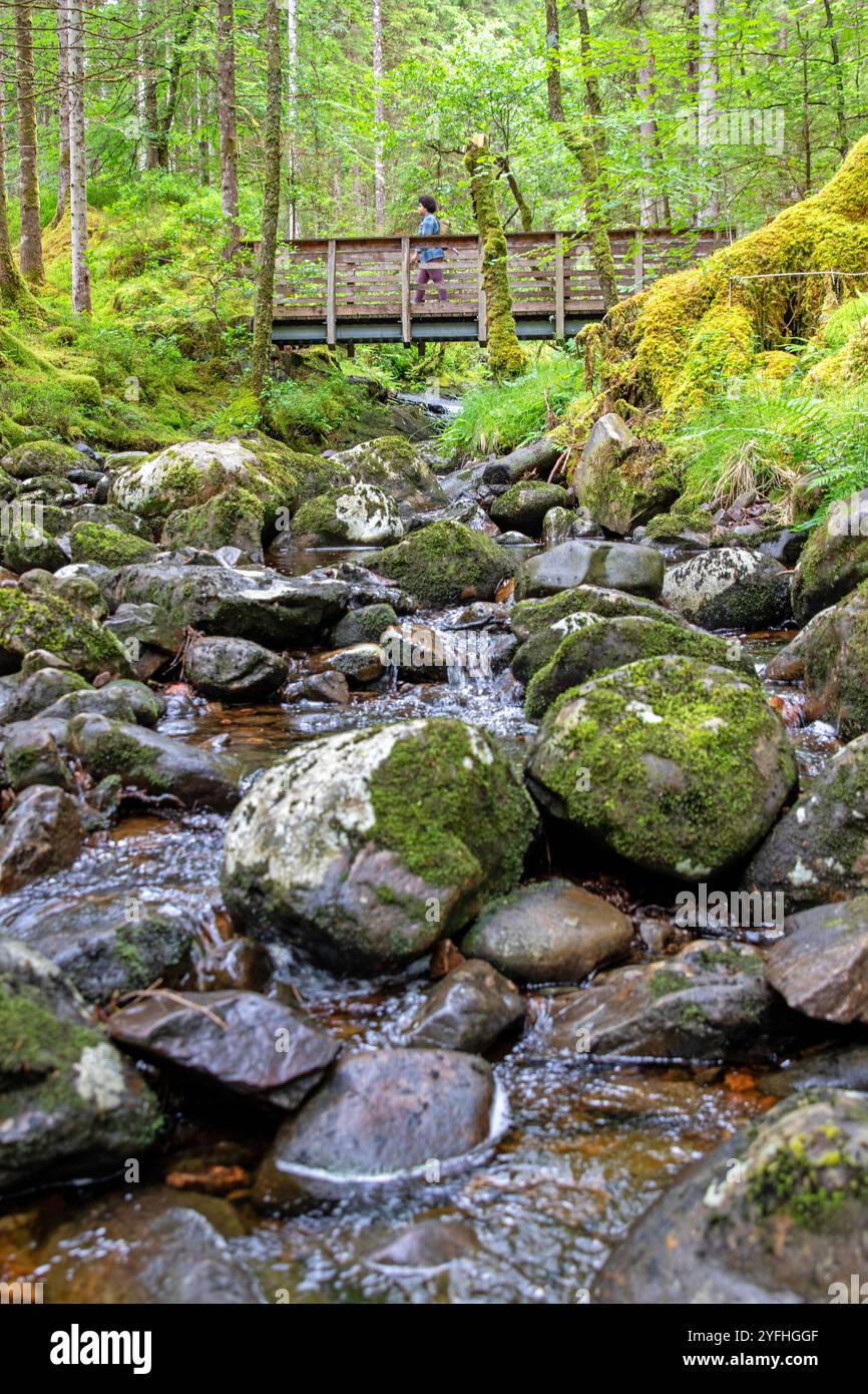 Escursionista che attraversa il torrente Allt na Calliche a Invergarry Foto Stock