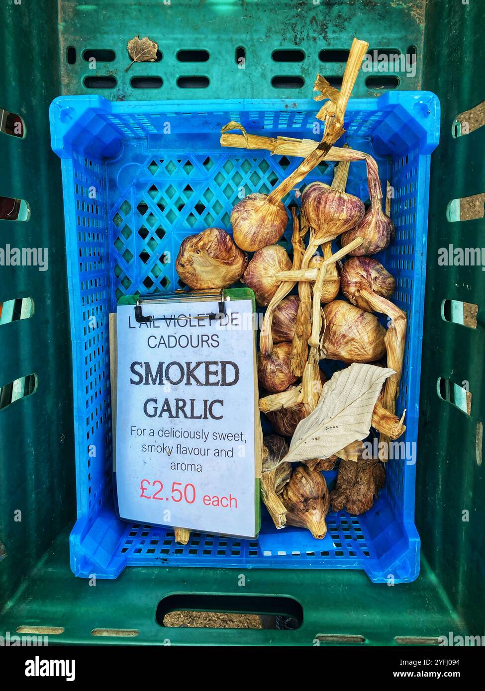 Le specialità di bulbi di aglio affumicati sono vendute al mercato agricolo locale - Immagine stock catturata con smartphone