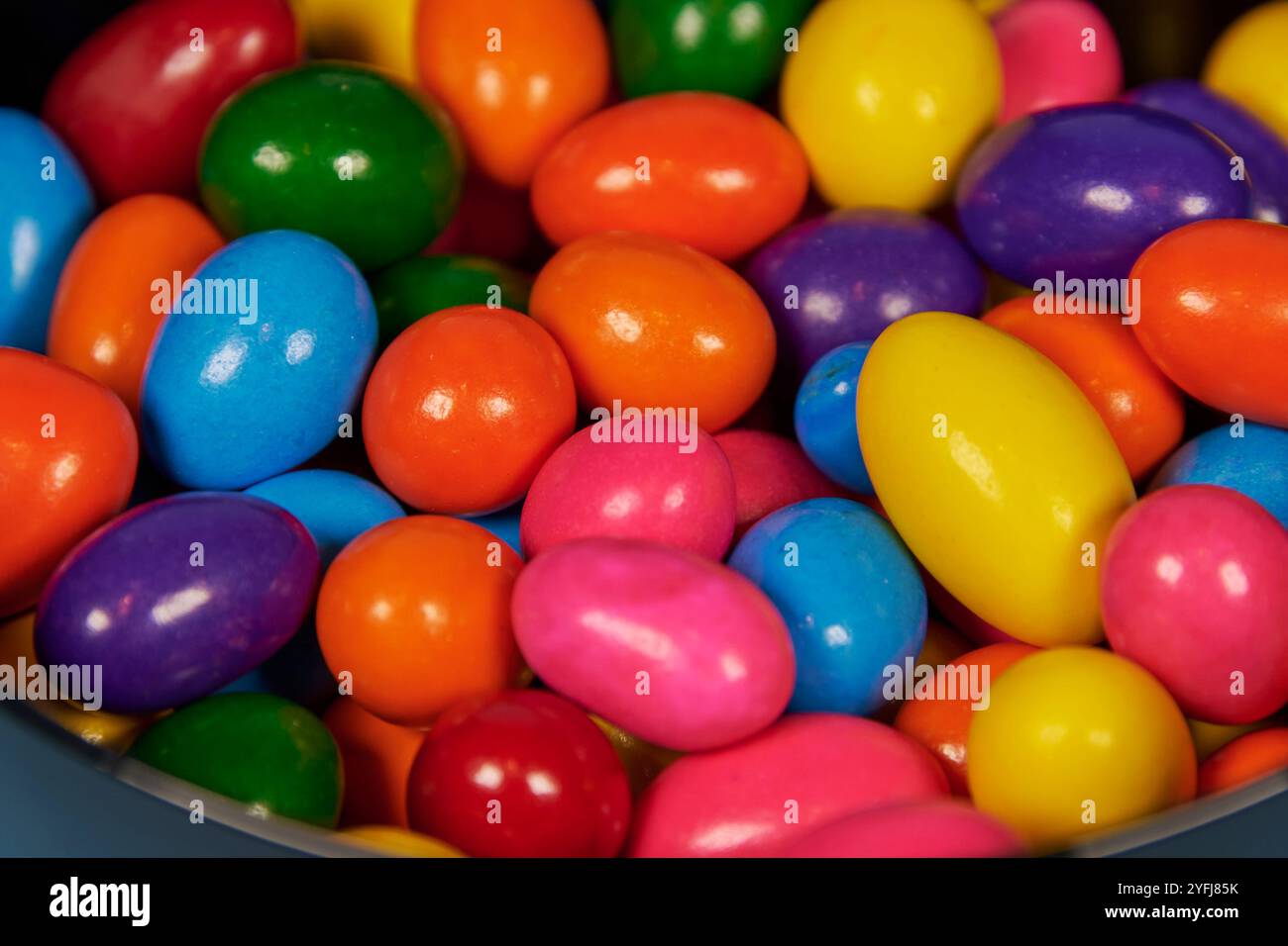 Palle di gomma da masticare di diversi colori in contenitori lucidi in terracotta con uno sfondo colorato omogeneo per il posizionamento del testo Foto Stock