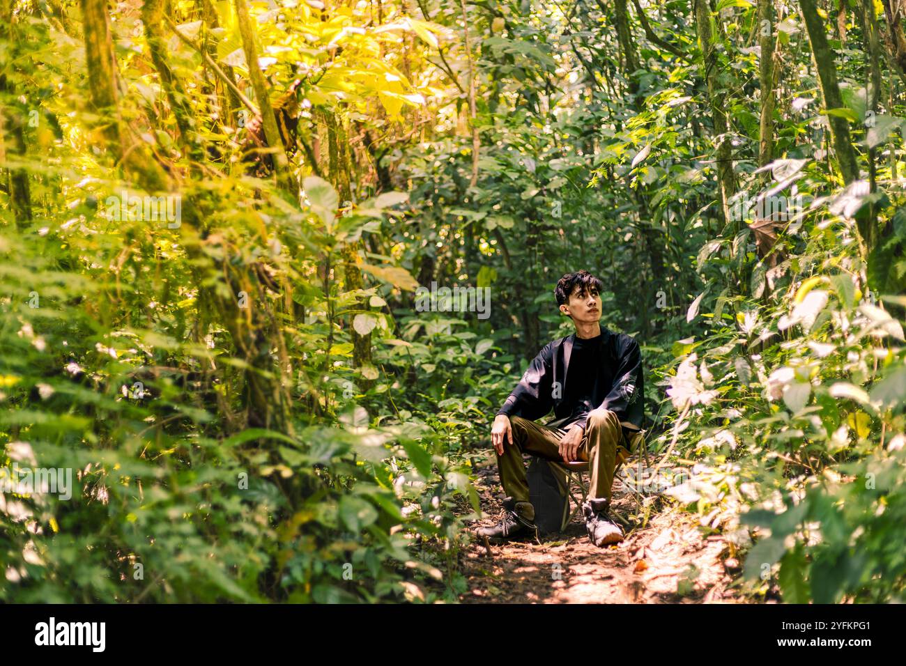 Uomo seduto e che si gode la grande vita all'aria aperta. Quiet Wilderness: Una tranquilla foresta incastonata nelle montagne. Foto Stock