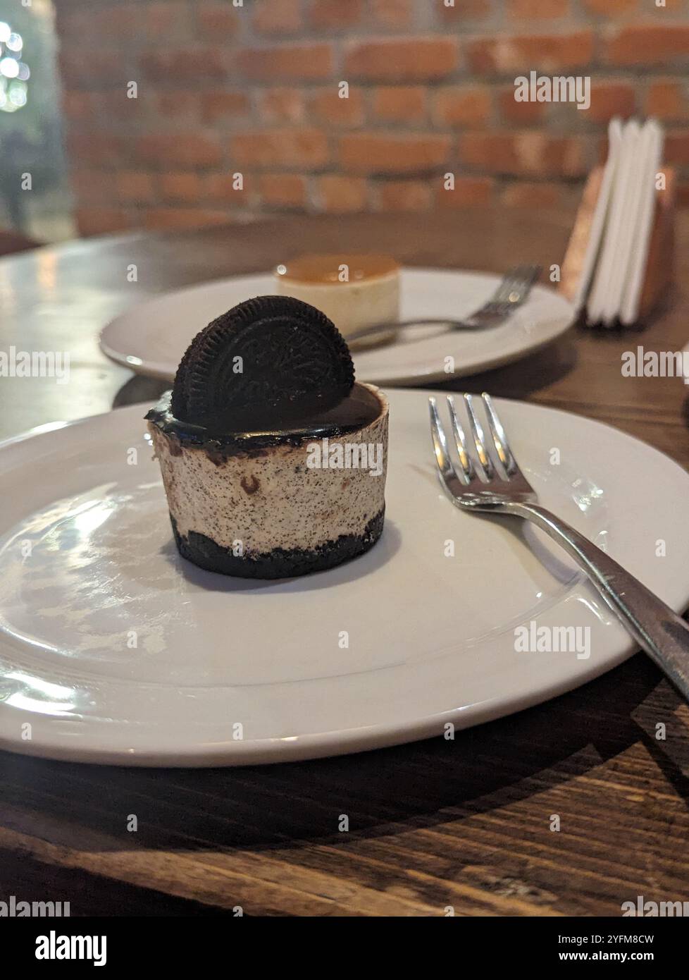 Cheesecake Oreo con una forchetta sul lato e mezza tostatura Oreo al forno - Immagine stock catturata con smartphone