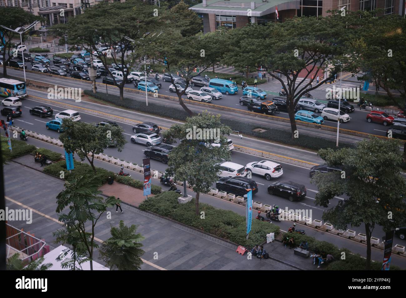 Giacarta, 1 novembre 2024. Un vivace angolo di Jakarta Street a mezzogiorno, pieno di traffico intenso e fiancheggiato da edifici alti, che catturano il vibr Foto Stock