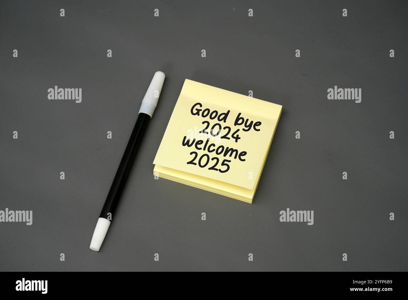 nota con testo scritto a mano addio 2024 e benvenuto 2025 con una penna su sfondo nero Foto Stock