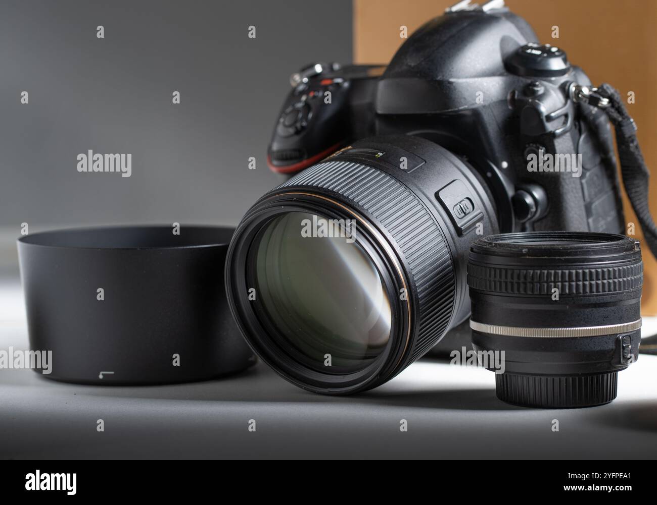 Fotocamera e obiettivi. Dettagli di una moderna fotocamera con obiettivo reflex singolo circondata da diversi obiettivi fotografici. Foto Stock