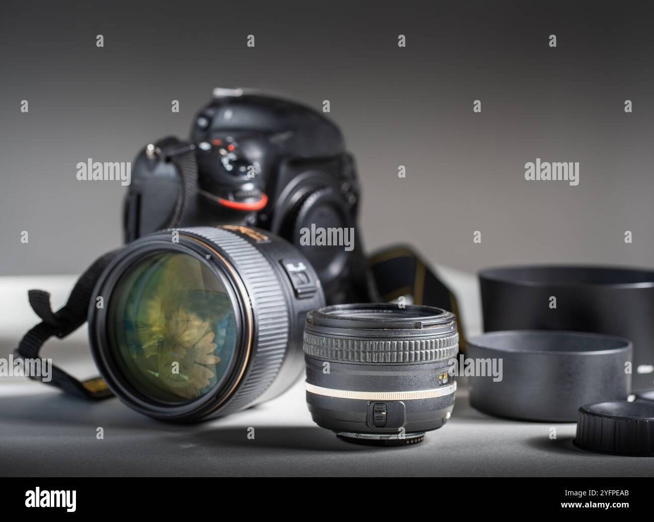 Fotocamera e obiettivi. Dettagli di una moderna fotocamera con obiettivo reflex singolo circondata da diversi obiettivi fotografici. Foto Stock