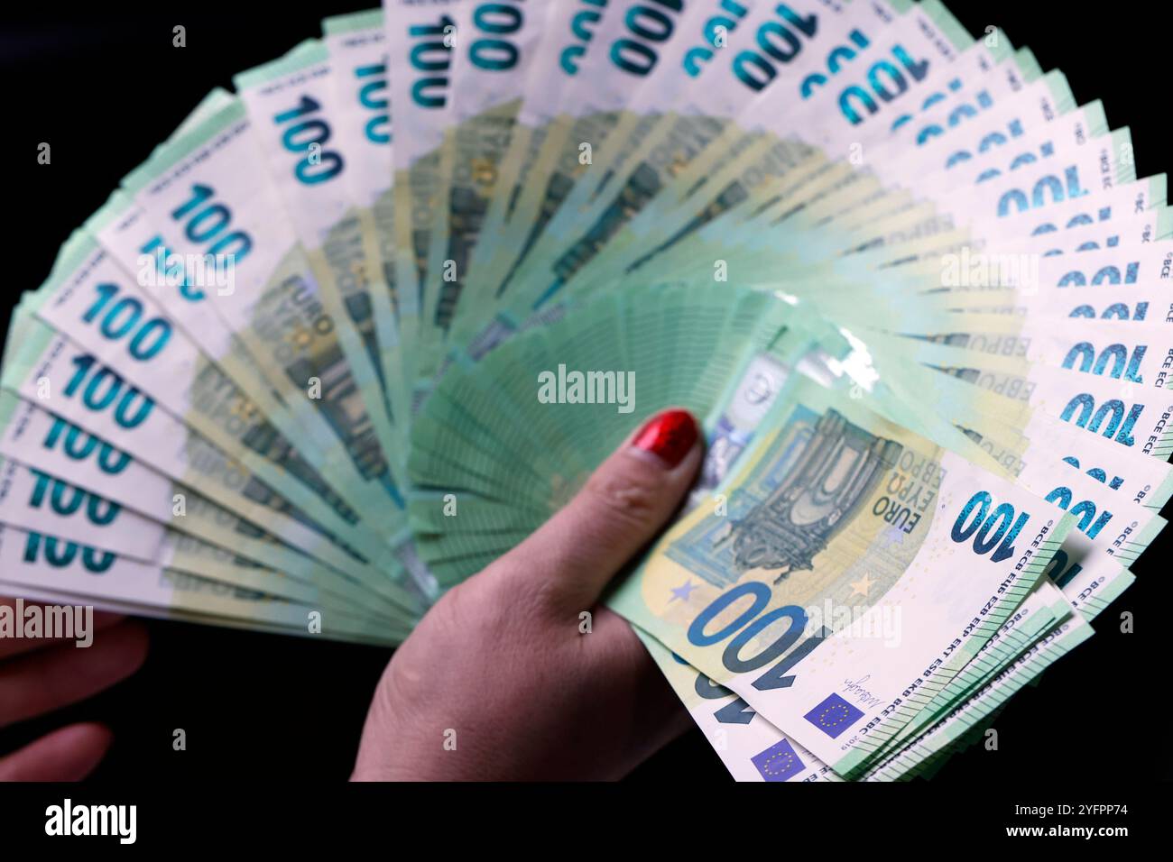 La mano femminile tiene in mano moneta europea Euro su sfondo nero: Banconote in euro da 100 euro. Tema dell'inflazione, delle imprese, dell'economia e della finanza. Foto Stock
