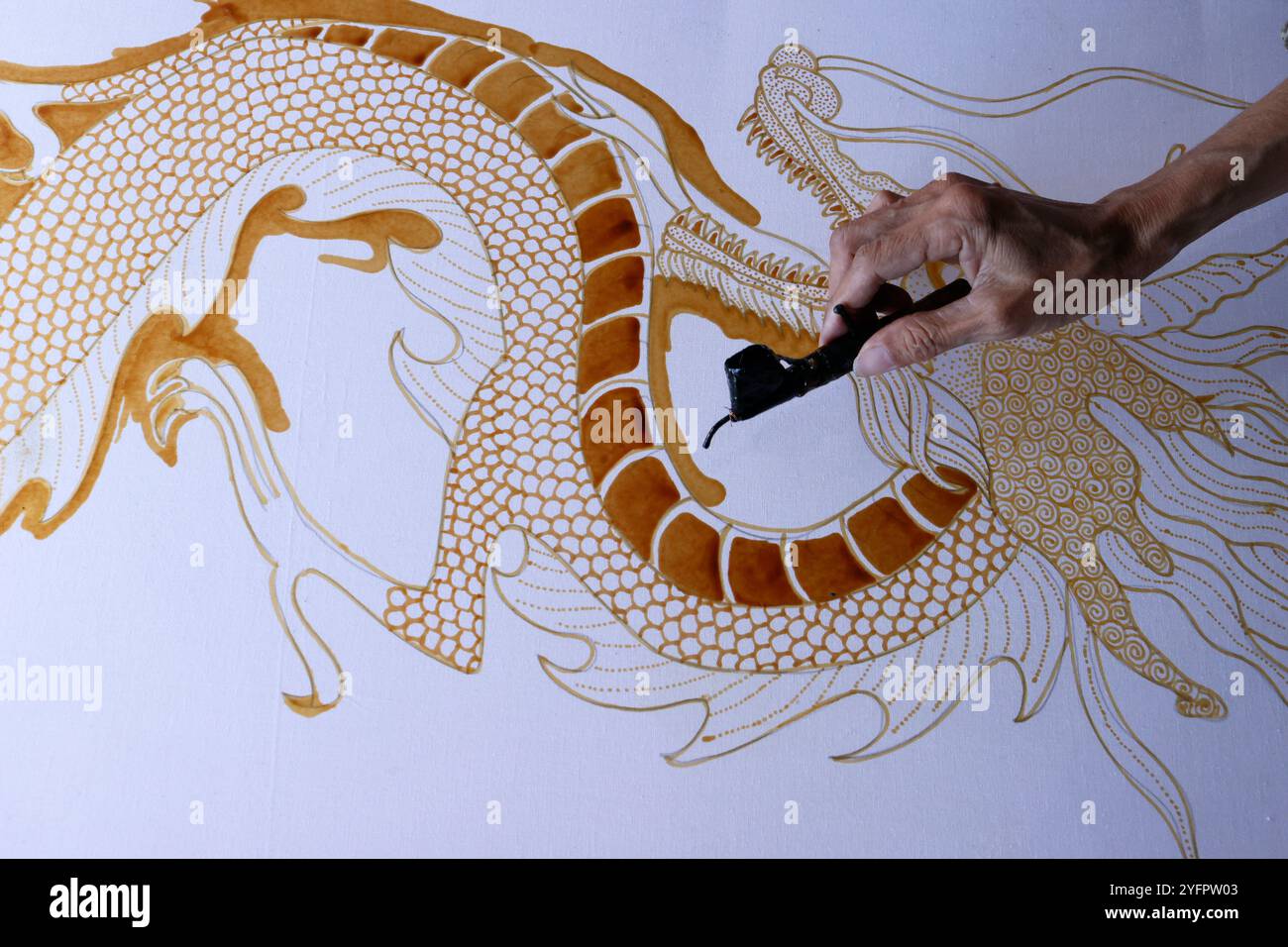 Produzione batik. Donna che usa cera calda per delineare un disegno di drago. Yogyakarta. Indonesia. Foto Stock