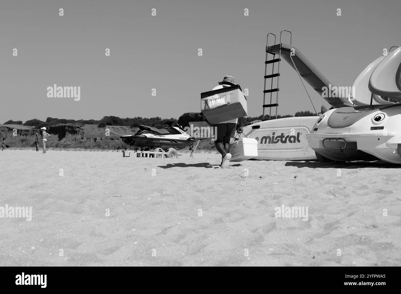 Monocromatico di un venditore di bola de berlim mentre si fa strada su una spiaggia sabbiosa Foto Stock