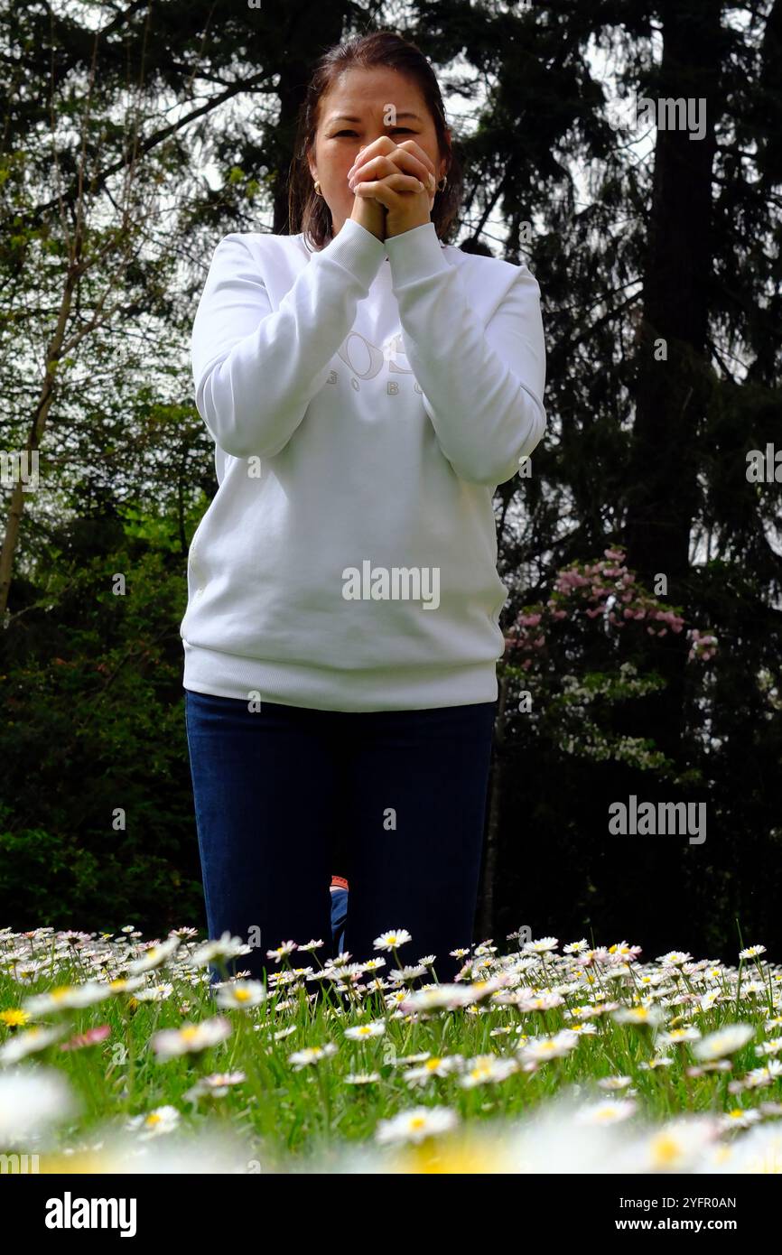 Donna cristiana che trascorre del tempo personale in un giardino e prega all'aperto. Foto Stock