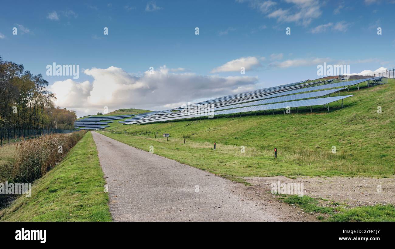 Energia rinnovabile nei Paesi Bassi: Grande parco di pannelli solari su una discarica riprogettata che mostra l'integrazione di energie rinnovabili con il paesaggio verde sotto Foto Stock