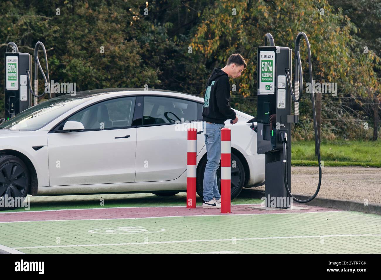 Energie rinnovabili nei Paesi Bassi: Parcheggio con veicolo elettrico in carica con persona, presso il polo energetico Green Planet di Pesse, Drenthe. Foto Stock