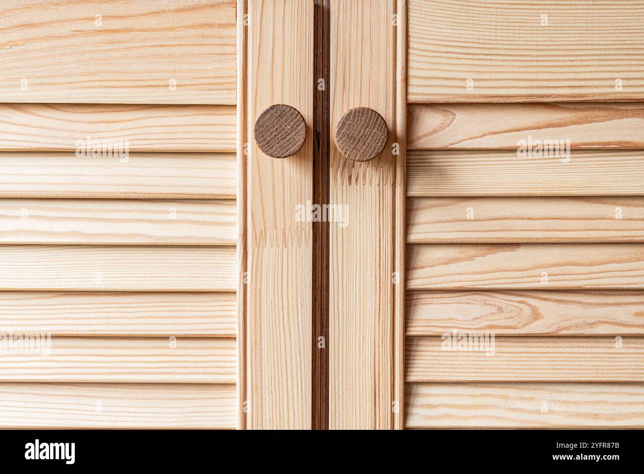 Porte con feritoie in legno con maniglie a pomello in legno per primo piano. Le porte a sfinestratura della cucina esterna sono realizzate in legno di pino chiaro con motivi a grana naturale Foto Stock