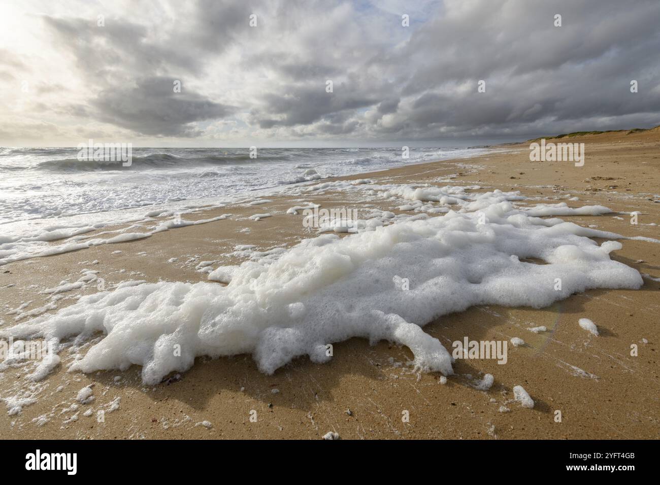 Schiuma di mare spazzata dal vento su una spiaggia nell'Oceano Atlantico Vicino Olonne sur mer in Francia Foto Stock