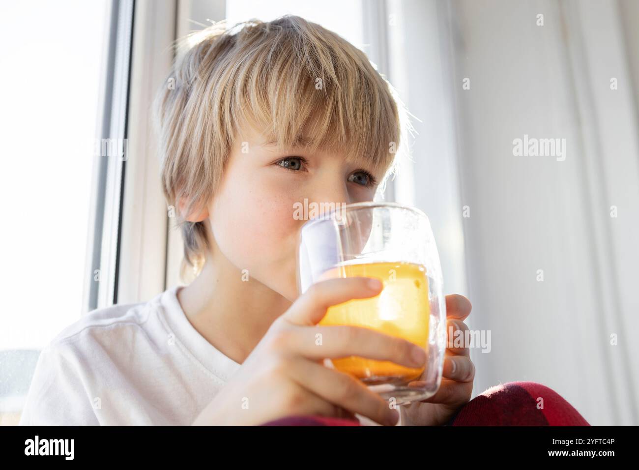 il bambino ama bere il tè da una tazza trasparente. primo piano sulla faccia del ragazzo. Dissetati con una bevanda deliziosa. Stile di vita Foto Stock