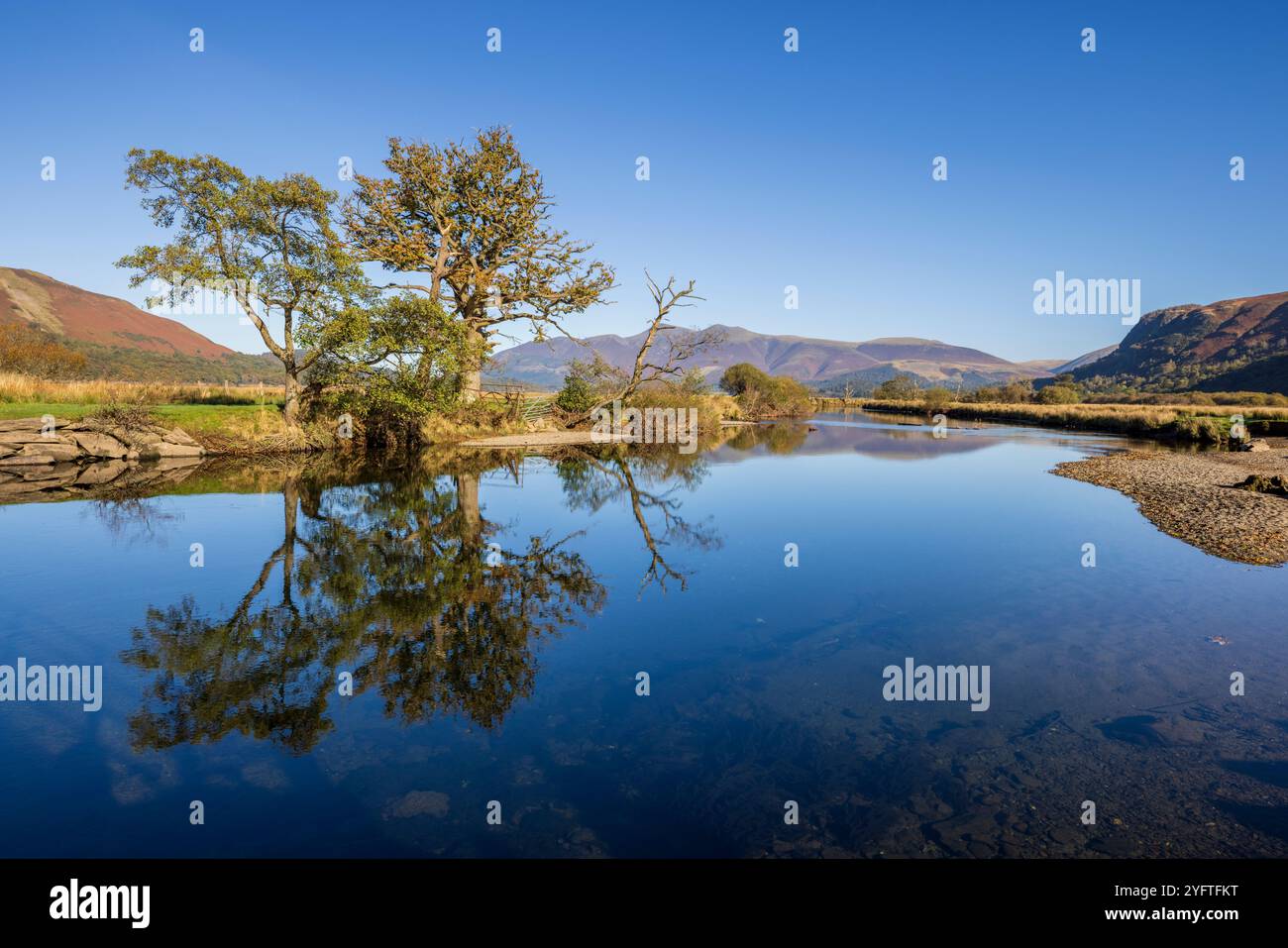 Le limpide acque del fiume Derwent che sfocia nel Derwent Water con il monte Skiddaw sullo sfondo, Lake District, Cumbria, Inghilterra Foto Stock
