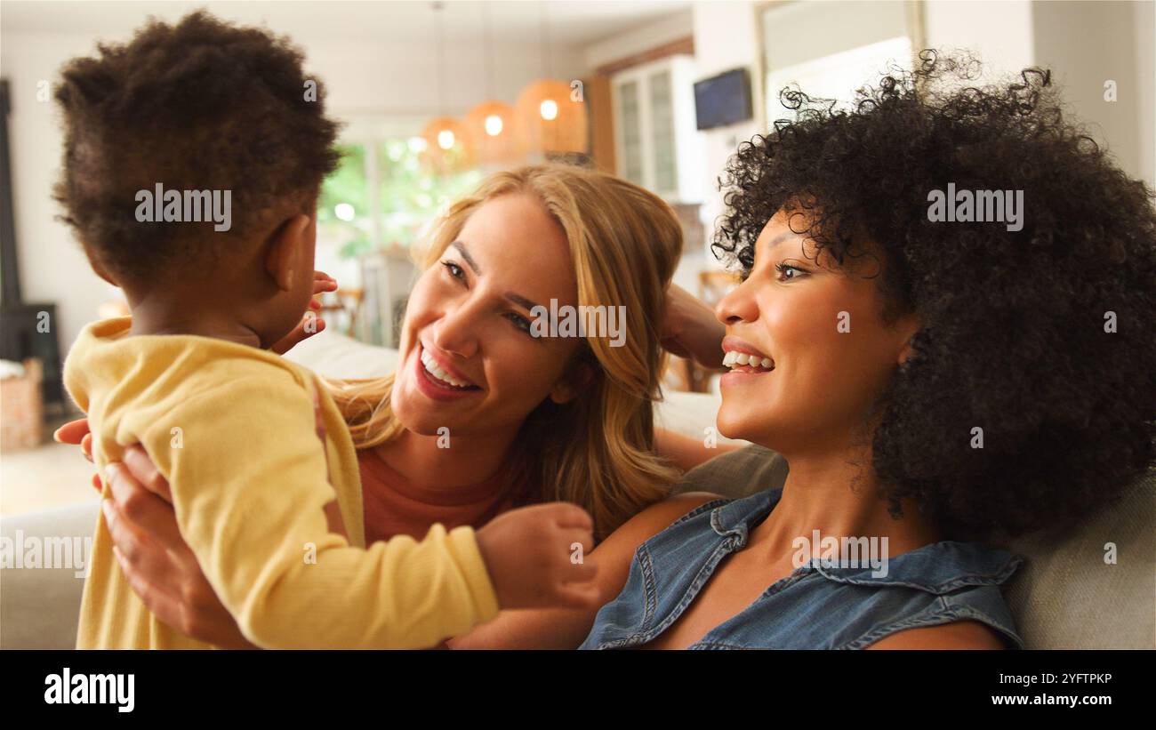 Le donne si divertono con un bimbo sorridente in un soggiorno accogliente. Foto Stock