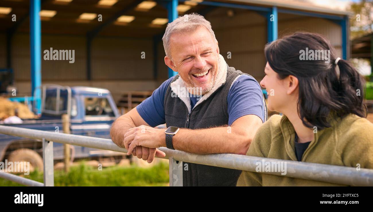 Lavoratori agricoli maschili e femminili che parlano a Yard by Fence Foto Stock