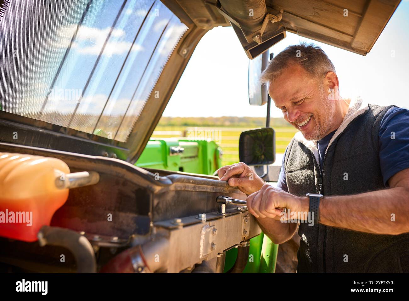 Primo piano dei macchinari per la riparazione dei lavoratori agricoli maschi maturi Foto Stock