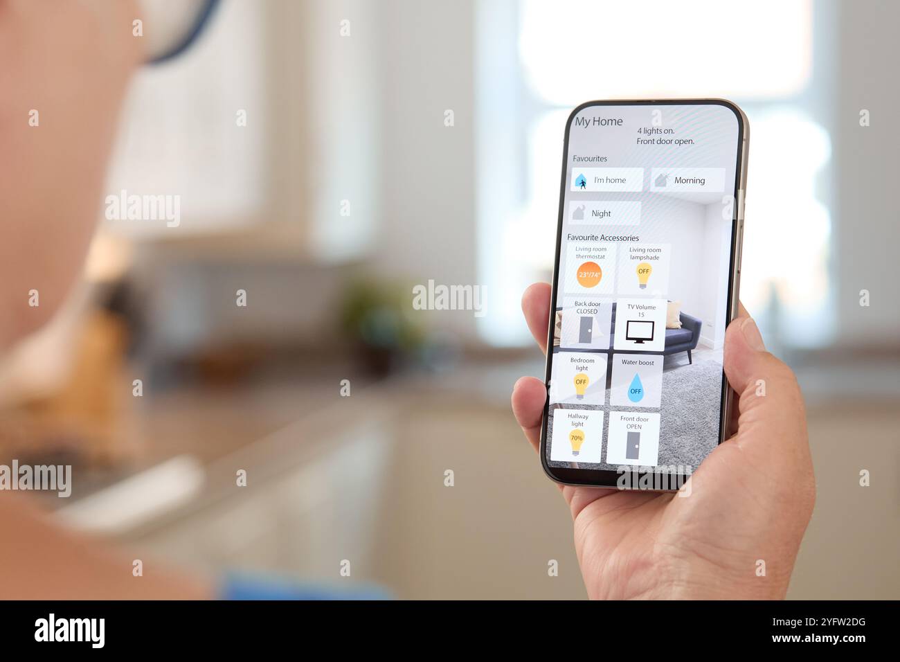 Una persona interagisce con uno smartphone per gestire vari dispositivi domestici intelligenti in un salotto contemporaneo. L'app visualizza le opzioni per l'illuminazione di Foto Stock