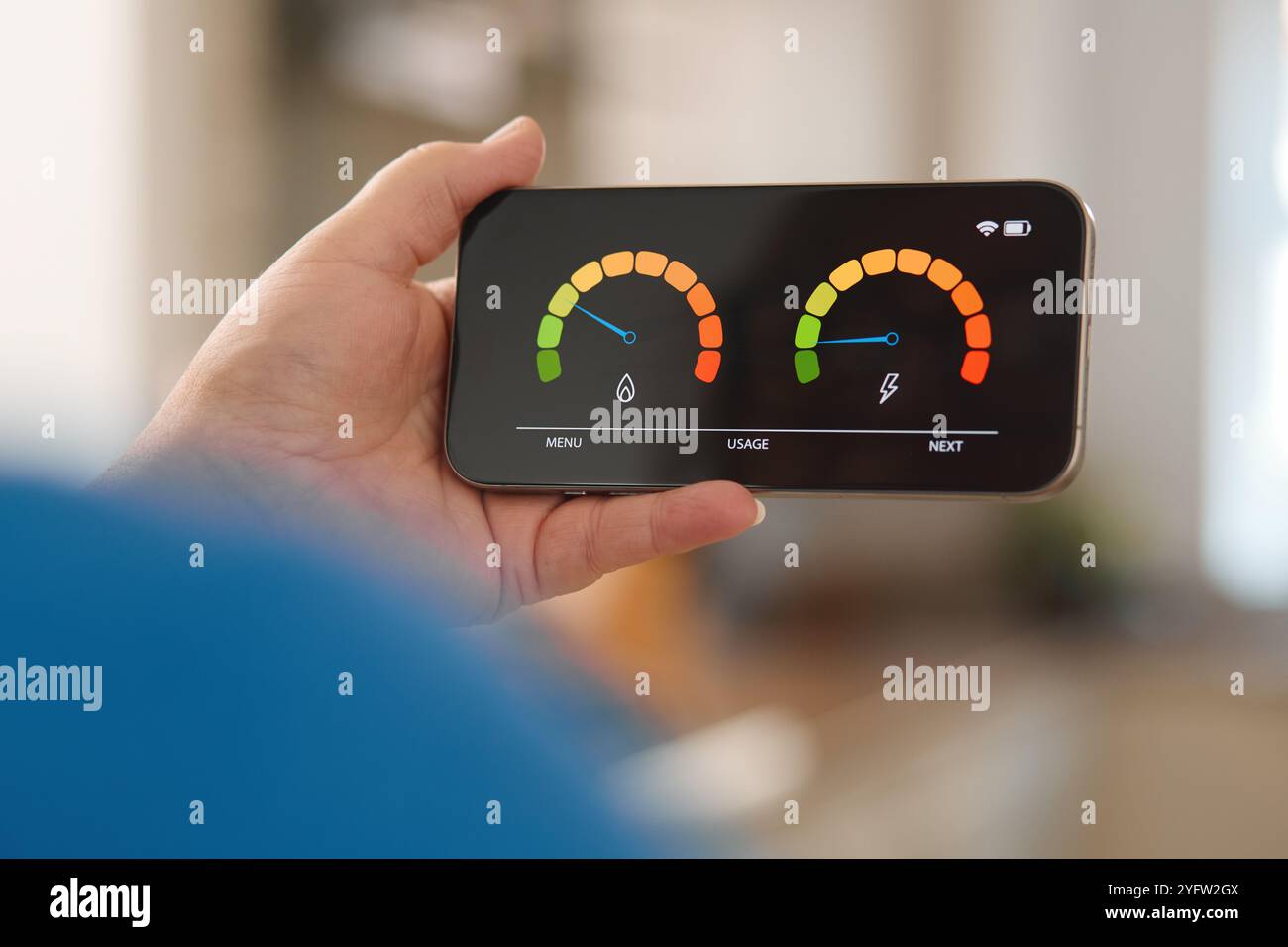 Una persona possiede un dispositivo mobile che mostra indicatori del consumo di energia e acqua. Il luminoso soggiorno offre un'atmosfera moderna, enfatizzando la sostenibilità Foto Stock