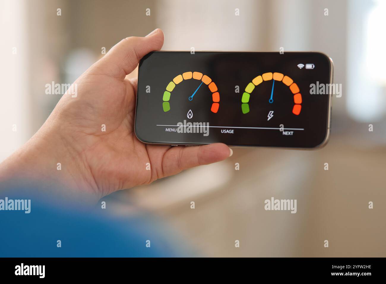 Una persona ha in mano uno smartphone che mostra indicatori colorati che indicano i livelli di consumo di acqua ed energia. Il display presenta segmenti verdi, arancioni e rossi Foto Stock