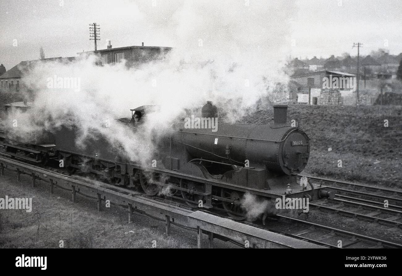 1950, storico, il vapore copre la locomotiva, n. 30325 su binario ferroviario. Fu costruita originariamente nel 1897 per essere utilizzata su London e Southern Western Raiways (LSWR) e successivamente fu utilizzata sulle Southern Railways (SR), prima di essere ritirata nel 1962 700. Foto Stock