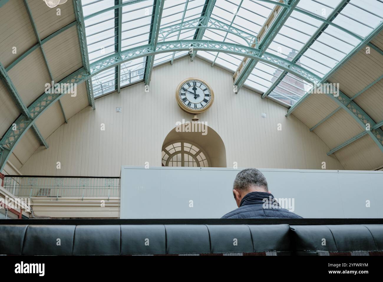 Un uomo solitario al Grainger Market, Newcastle. L'orologio è visibile appena prima di mezzogiorno. Foto Stock