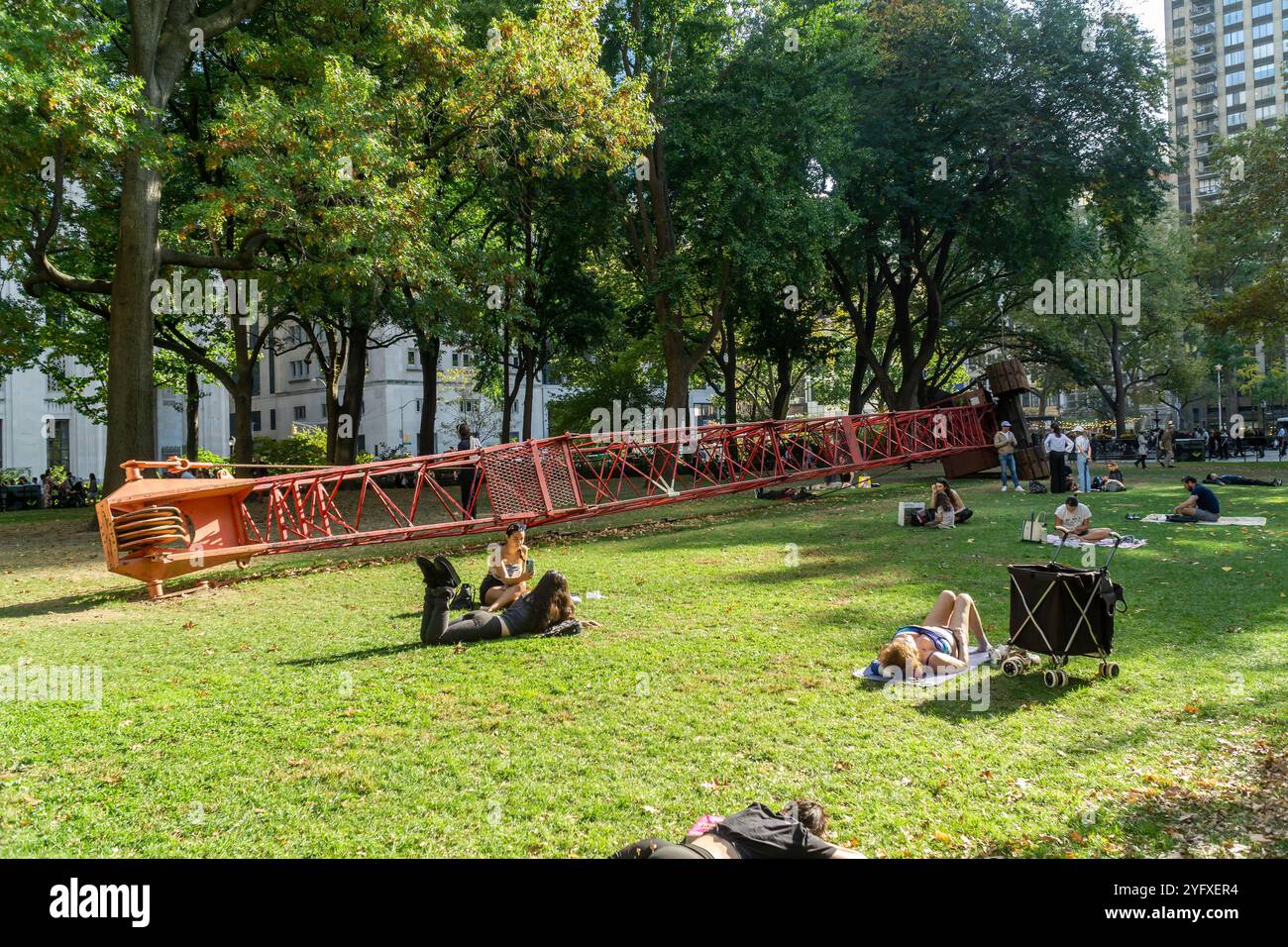 I visitatori del Madison Square Park possono godersi il clima caldo e instagionale che prende il sole accanto alla "gru fissa" di Nicole Eisenman, sul prato ovale, visto giovedì 31 ottobre 2024. Le temperature per i festeggiamenti di Halloween raggiunsero i 70 superiori (© Richard B. Levine) Foto Stock