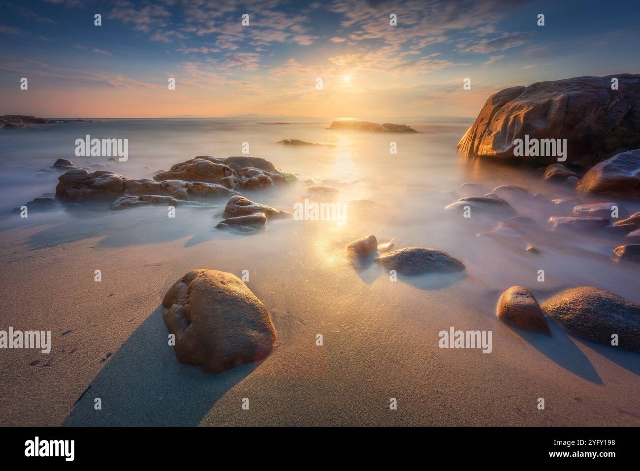 Scogli nella spiaggia di Cala Violina in Maremma al tramonto, Toscana. Destinazione di viaggio nel Mediterraneo. Italia, Europa. Esposizione lunga Foto Stock