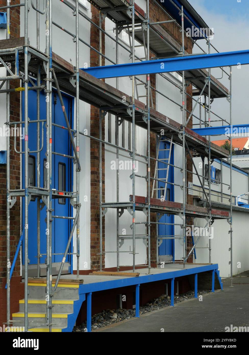 La composizione dell'impalcatura grigia davanti al cancello industriale blu è una prospettiva insolita e conferisce all'immagine un'estetica moderna. Foto Stock