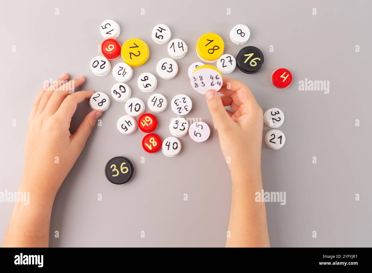 Gioco di allenamento DIY Math per bambini, mani che selezionano tappi per bottiglie di plastica con informazioni sulla moltiplicazione, divertenti attività educative per i bambini, un modo efficace per farlo Foto Stock