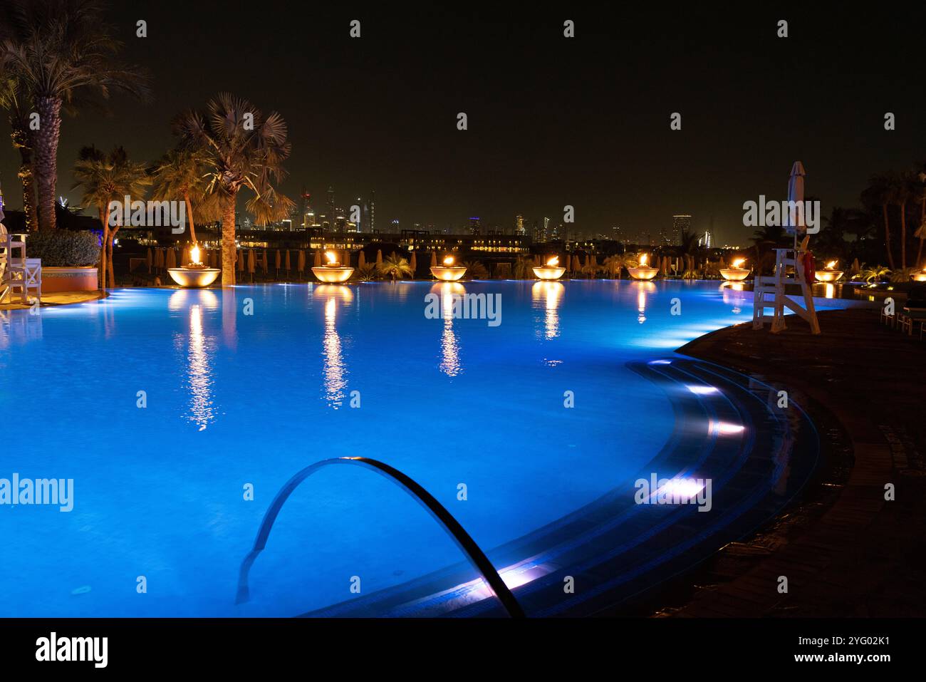 Scena serale intorno alla piscina reale all'hotel Atlantis The Palm con illuminazione dai bruciatori di fuoco, Dubai, Emirati Arabi Uniti Foto Stock