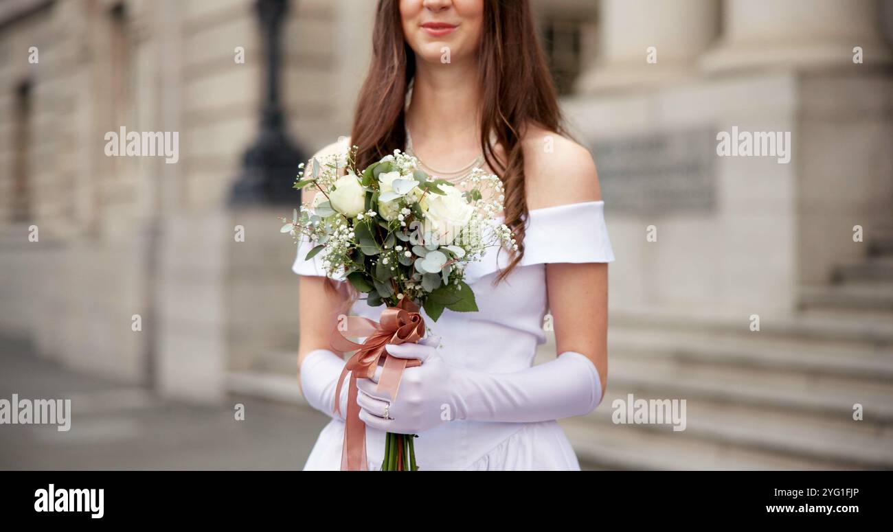 Mani, donna e bouquet con matrimonio in città per amore, abiti felici e bianchi per festeggiare in strada a corte. Sposa, persona e fiori per l'evento Foto Stock