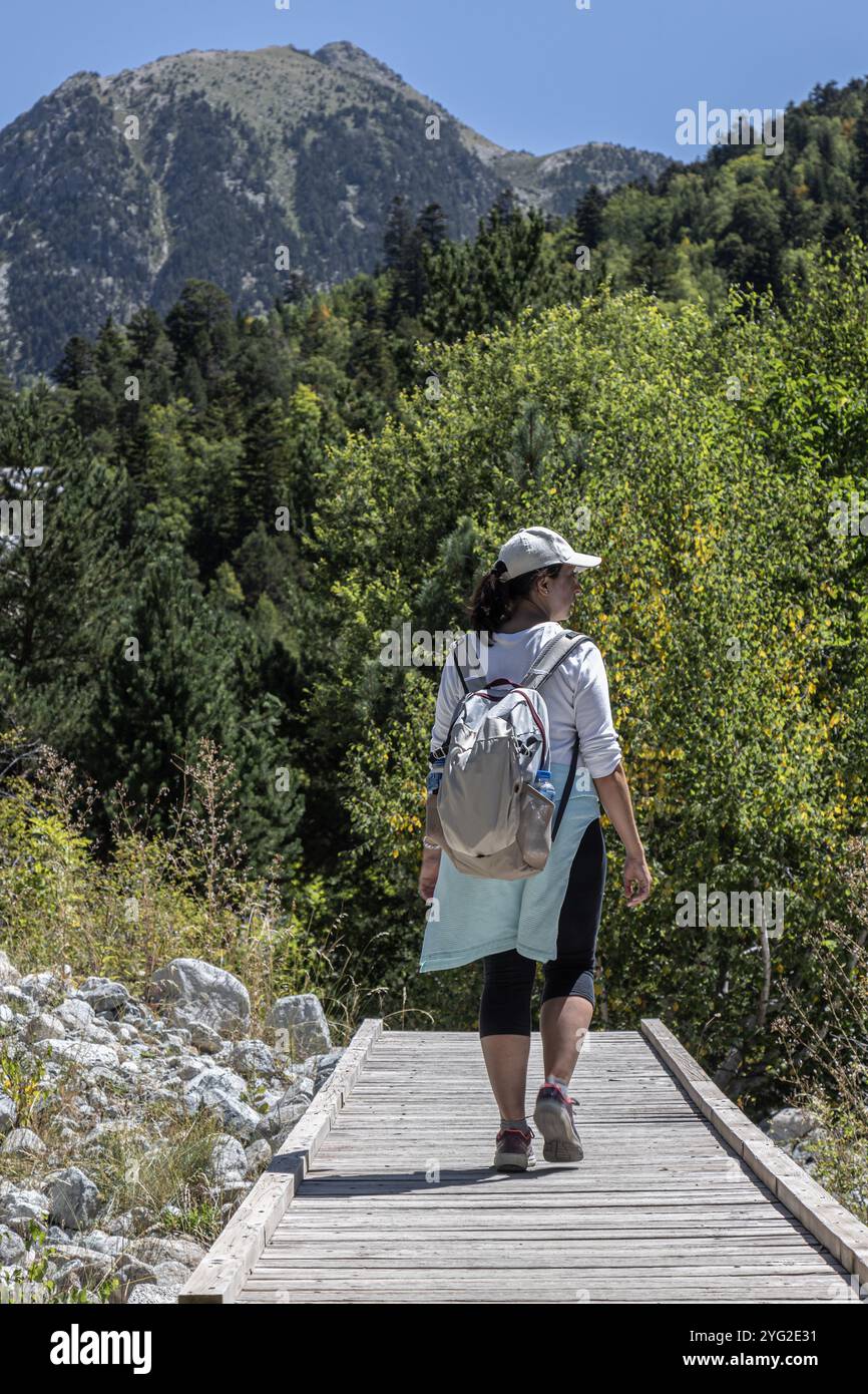 Turista caucasico di mezza età che cammina sul piccolo ponte di legno nella montagna spagnola dei Pirenei Foto Stock