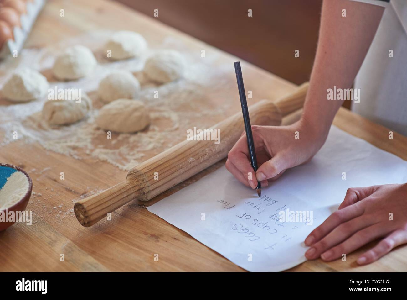 mani, cuocere e scrivere una ricetta in cucina per preparare l'impasto, controllare i passaggi e le istruzioni. Persona, casa e carta con elenco di controllo per Foto Stock