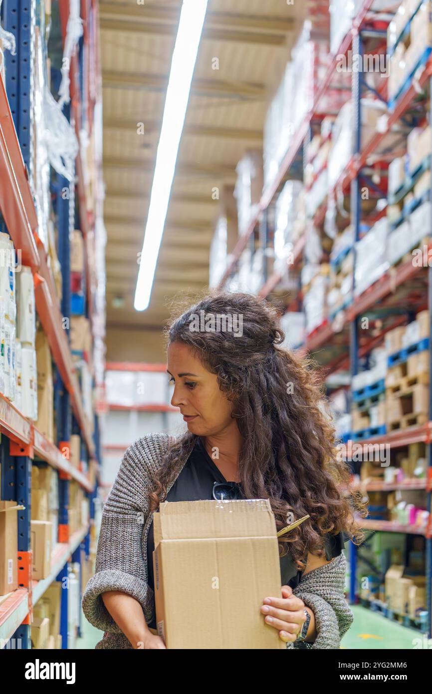Donna di mezza età rispettosa dell'ambiente che fa acquisti con scatola di cartone per la sostenibilità al supermercato Foto Stock