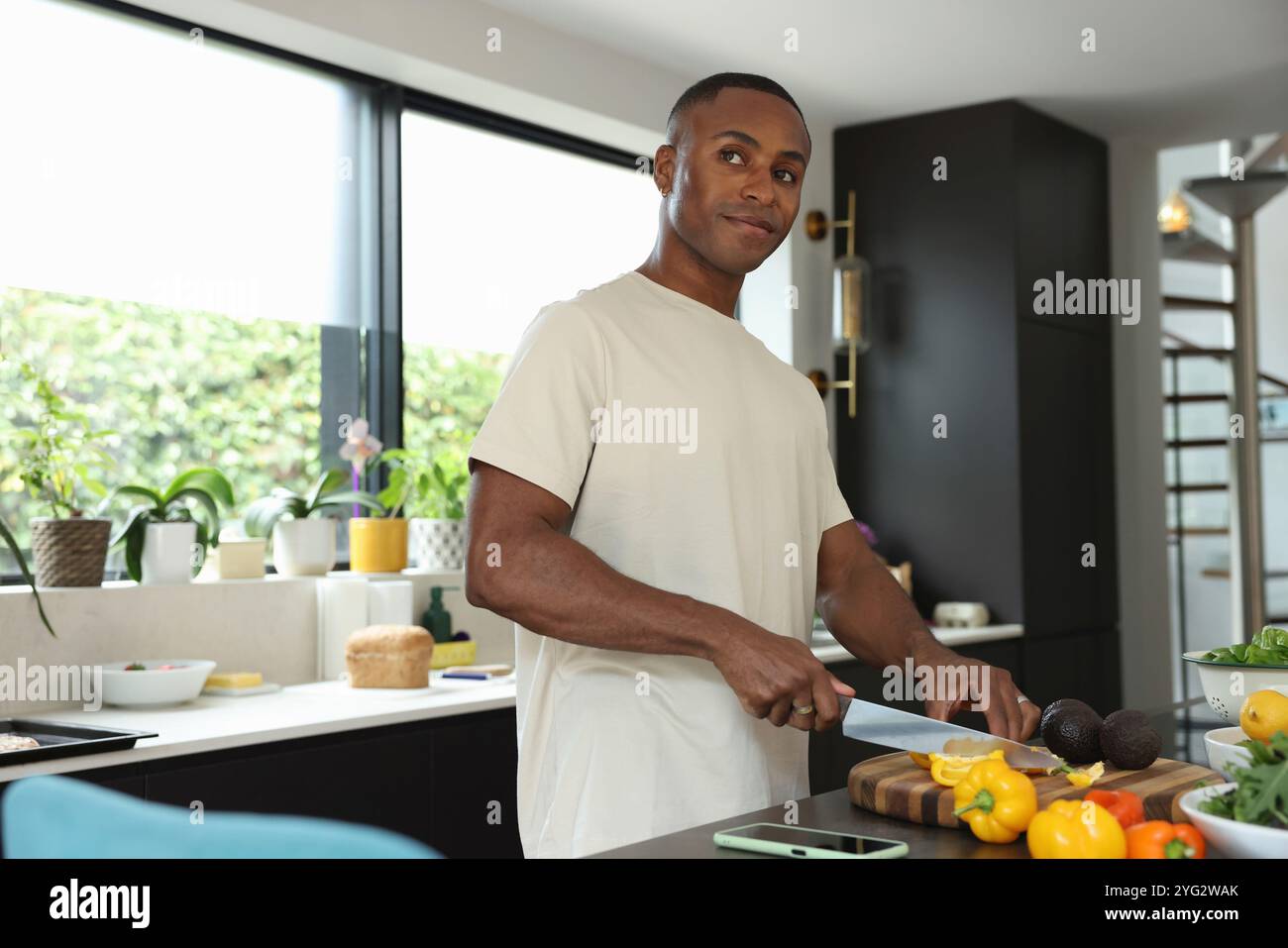 Uomo che taglia peperone giallo in cucina Foto Stock